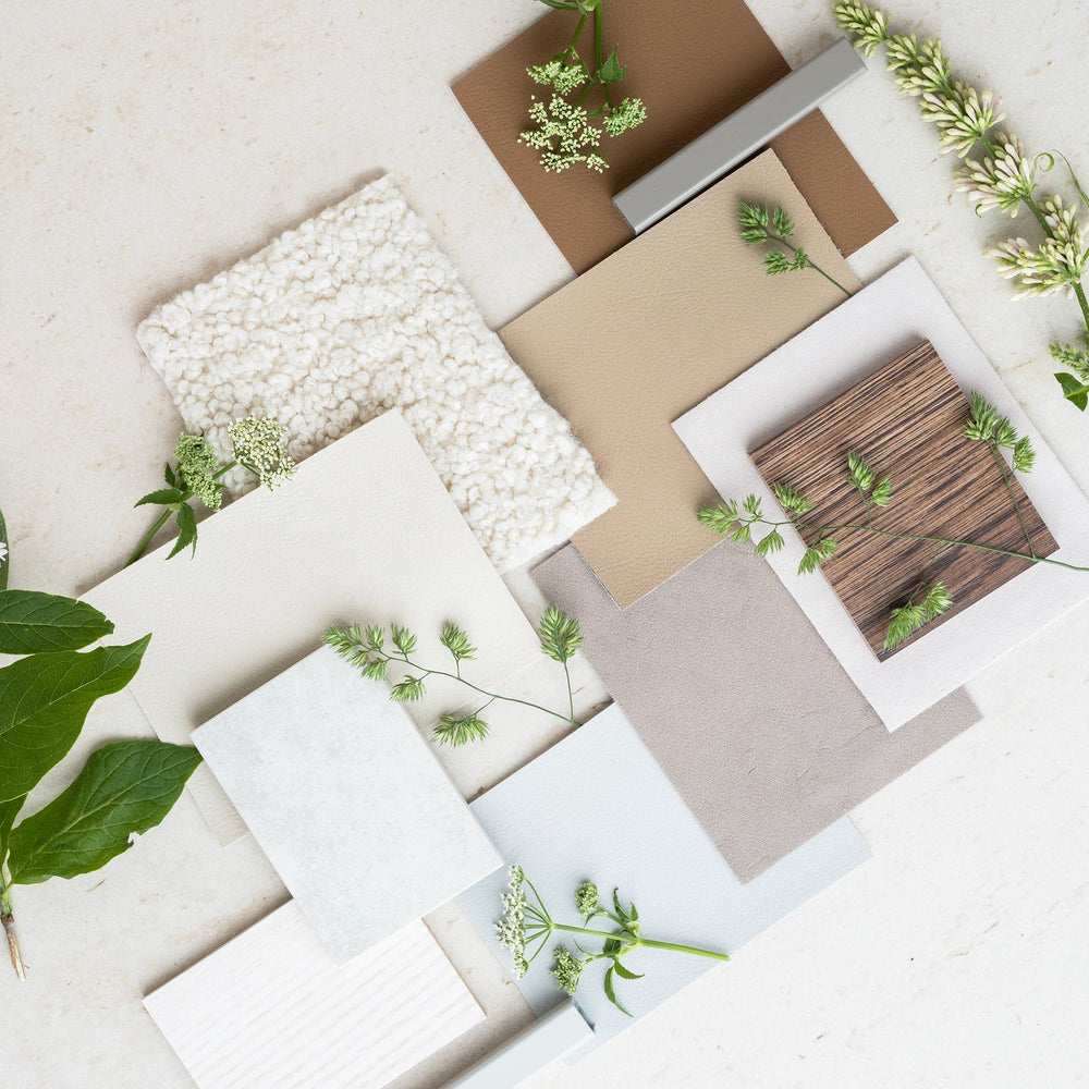 Scandinavian-inspired material samples with boucle, vegan leather, wood veneer, and neutral-toned swatches styled with greenery – by Crea custom furniture palette.