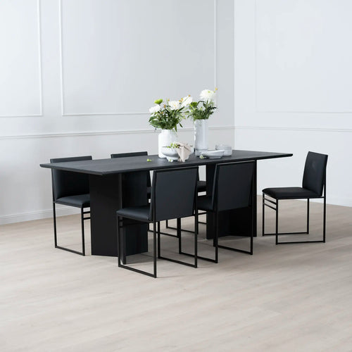 Ann dining table in black oak with modern chairs, showcasing sleek design and elegant style in a minimalist setting.