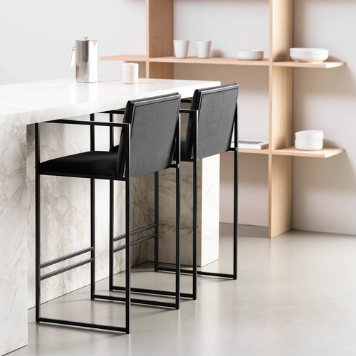 Bruno bar stools in black velvet at a modern kitchen island, showcasing Scandinavian design and sleek armrests.