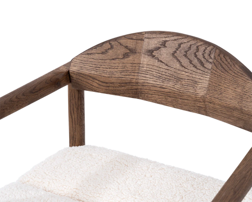 Close-up of Carl Bar Stool backrest in dark oak showing the curved solid wood joinery and grain detail above ivory bouclé seat | by Crea.