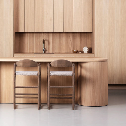 Dark oak bar stools with greige bouclé in a modern kitchen setting, showcasing elevated style and premium materials.