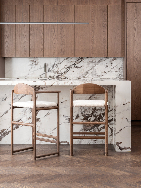 Oak Bar Stool Carl in dark oak with ivory bouclé near a marble kitchen counter
