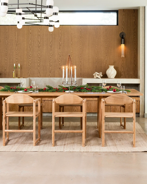Scandinavian Christmas dining setup with by Crea Erik Dining Chairs in oak, styled with greenery, candles, and festive tableware.