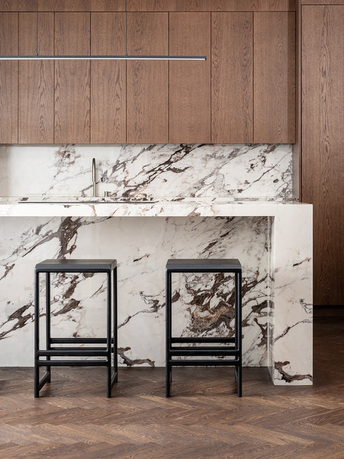 Modern kitchen featuring black oak bar stools and a stylish marble countertop with wooden cabinets.