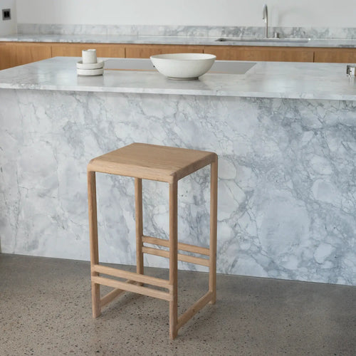 Oak Bar Stool in solid wood placed near a modern kitchen island with marble countertop.