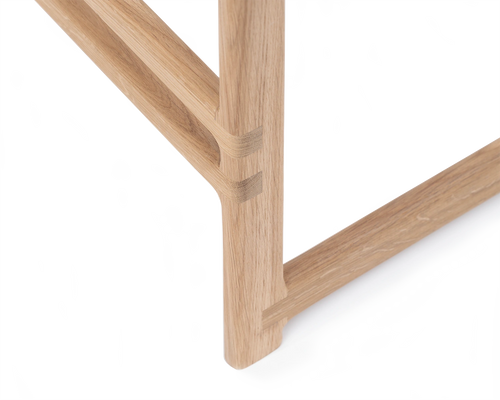 Close-up of the Eva Bar Stool by Crea showcasing the hand-crafted joinery and rounded footrest in solid light oak, emphasizing Scandinavian woodworking and minimalist detail.