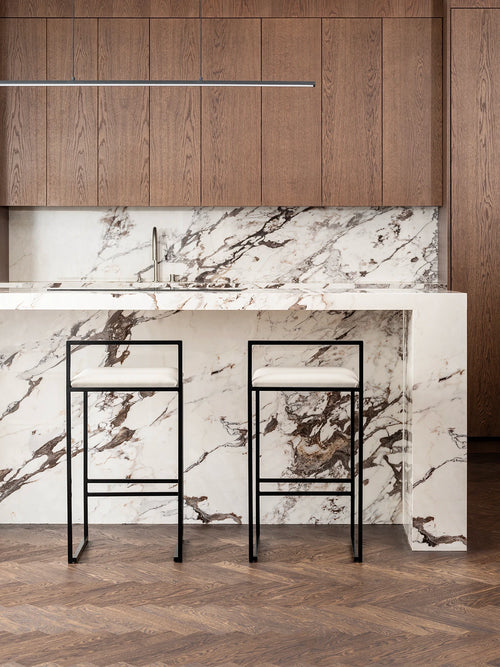 Bar Chair Freja with black frame and ivory leather cushion at a modern kitchen island with marble countertop.