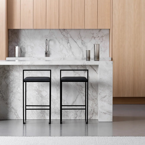 Freja bar stools in black leather with minimalist design at a modern kitchen island with marble countertop.