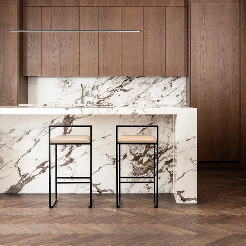 Freja bar stools with black frames and latte leather seats at a modern kitchen island with white marble countertop.