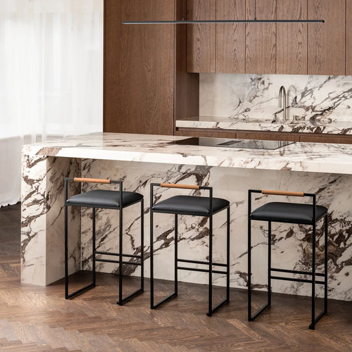 Freja bar stools with black frames and leather seats in a modern kitchen with marble countertop.
