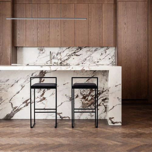Freja bar stools in black velvet by a sleek marble and wooden kitchen island, showcasing timeless design.