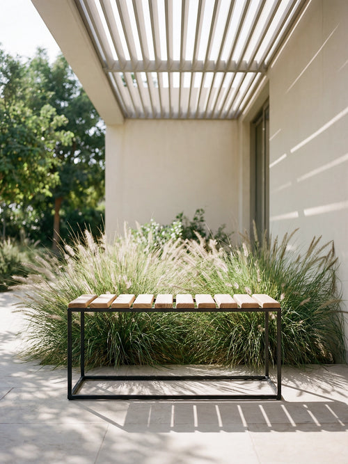 Wooden bench in a garden setting with a modern building and tall grasses.