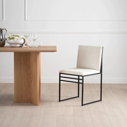 Isabell dining chair in ivory vegan leather beside modern wooden dining table.