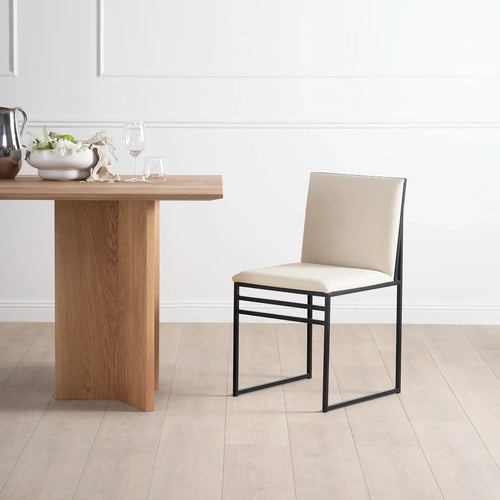 Isabell dining chair in sand leather with black frame, placed next to a dining table in a modern interior.