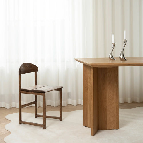 Karin dining chair in dark oak beside a modern wooden table, showcasing elegant grain and refined design in a minimalistic setting.