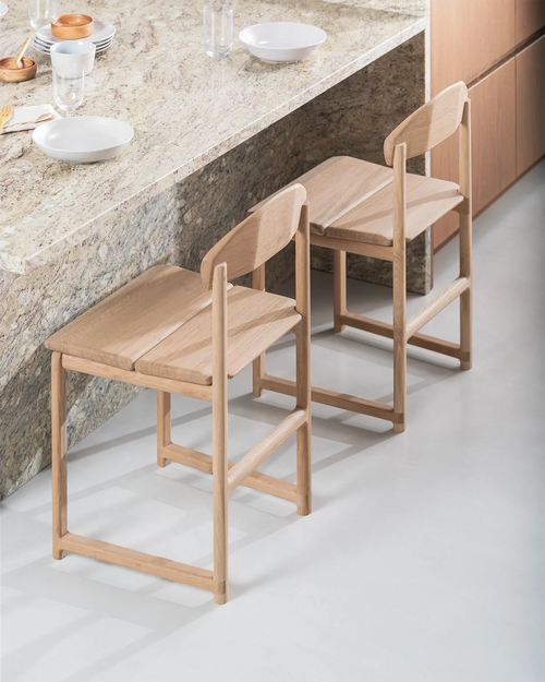 Karin dining chairs by by Crea in solid oak, placed at a stone kitchen island, showcasing minimalist Scandinavian craftsmanship and a warm natural finish.