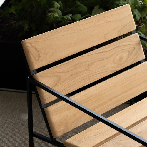 Close-up of Kenny Lounge Chair by by Crea, showing teak wood slats and black steel frame. Handmade designer outdoor furniture, part of the exclusive Scandinavian furniture collection.