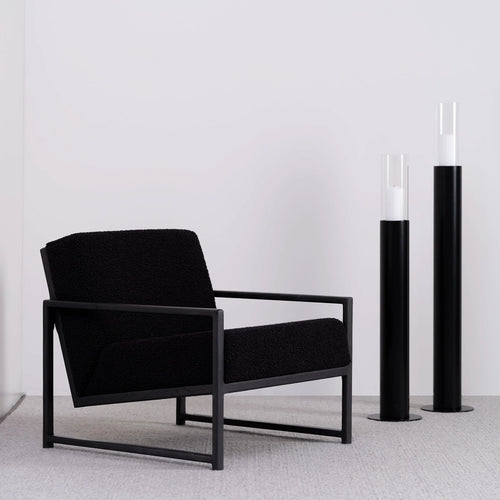 Minimalist black oak armchair with black bouclé seat, featuring modern design and relaxed support.