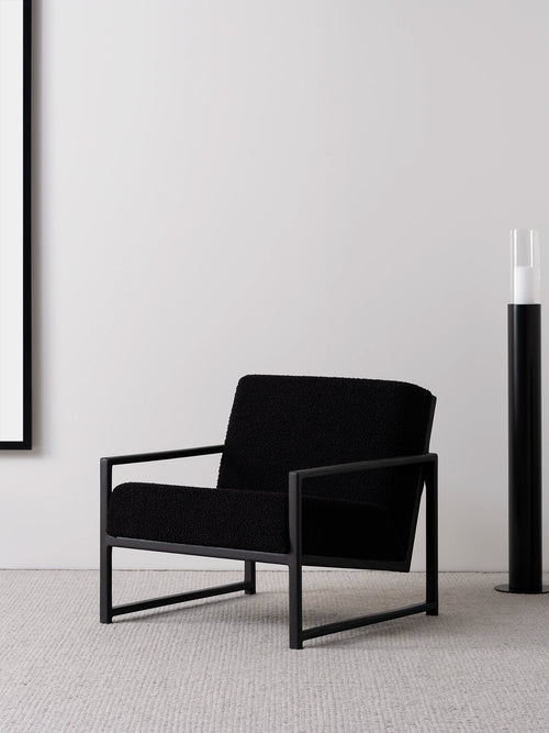 Armchair Einar in black oak frame and black bouclé cushion, minimalist design with modern styling.