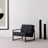 Black oak armchair with jade black leather seat, showcasing sleek Scandinavian design in a modern interior.