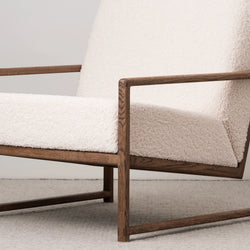 Dark oak armchair with soft ivory bouclé upholstery, adding warmth and Scandinavian comfort to any cozy space.