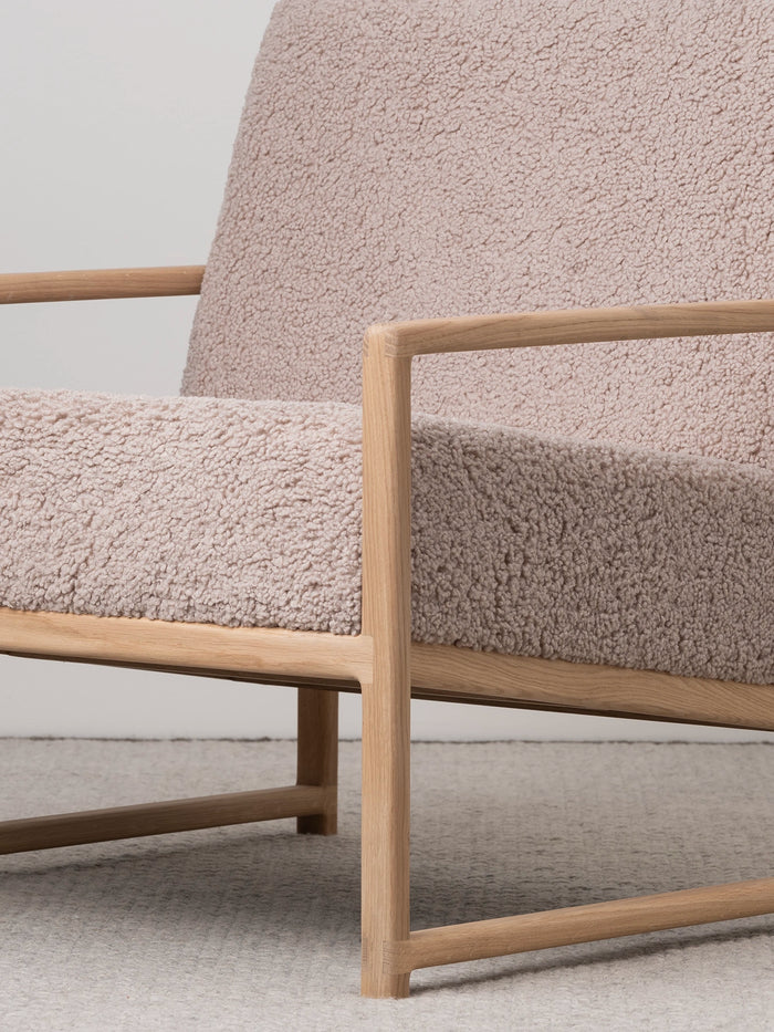 Armchair Einar with oak frame and soft greige bouclé cushion, ideal for modern living spaces.