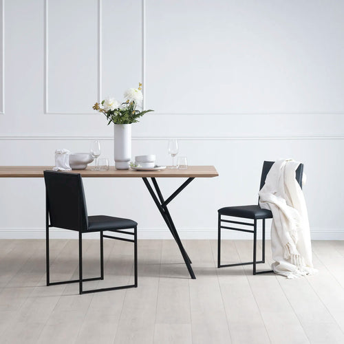 Melker dining table in black with oak top, surrounded by modern chairs and decorative vase, showcasing stylish dining setup.