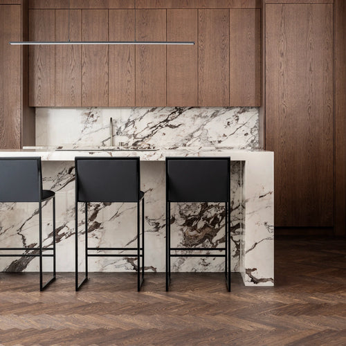 Philip black bar stools with high backs at a modern kitchen island with marble countertop.