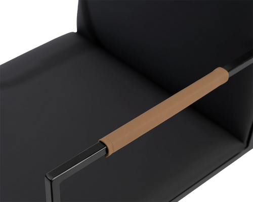 Close-up of Sella Dining Chair’s tan vegan leather-wrapped armrest by Crea, set against black frame and seat, showcasing detail and Scandinavian elegance.