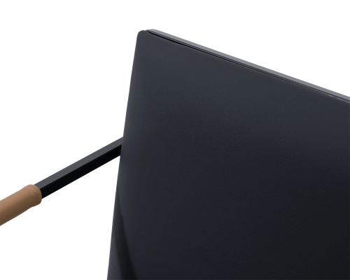 Detail of the Sella Chair backrest in smooth vegan leather with black steel frame and tan armrest accent, minimalistic Scandinavian design.