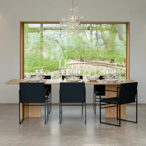 Modern dining space featuring Sella dining chairs in black leather around a stylish wooden table.