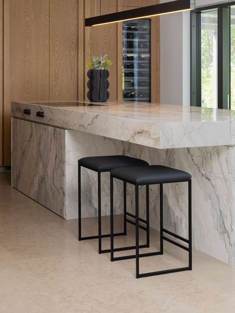 Bar Stool Svea – Black – Jade Black Leather at a modern kitchen island with marble countertop.