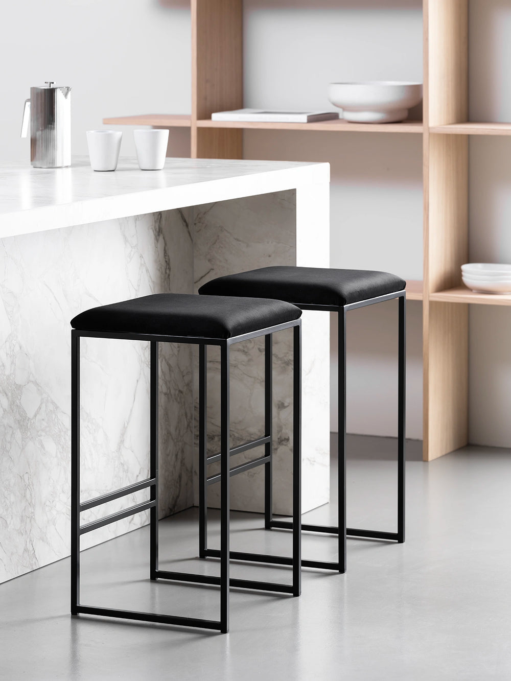 Stylish black bar stools with velvet seats, perfect for modern kitchen islands or high tables.