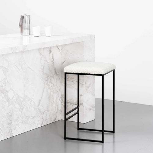 Svea bar stool with black frame and ivory bouclé seat, featuring a modern design in a contemporary kitchen setting.