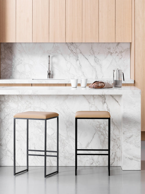 Bar Stool Svea in black frame with latte leather seat in a modern kitchen setting.