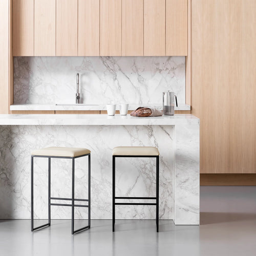 Minimalistic Svea bar stools with sand leather seats and black frames in a modern kitchen setting.