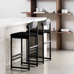 Sleek black oak bar stools with black bouclé seats at a modern kitchen counter.