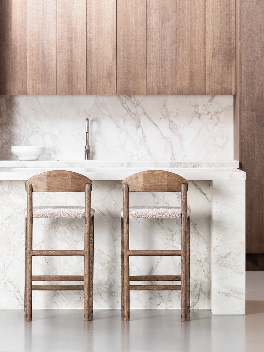 Oak Bar Stool Ted in dark oak with greige bouclé seat set at a stylish marble kitchen island.