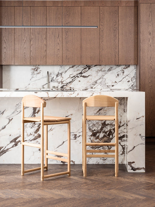 Oak Bar Stool in a modern kitchen setting with marble countertop and wooden cabinets.