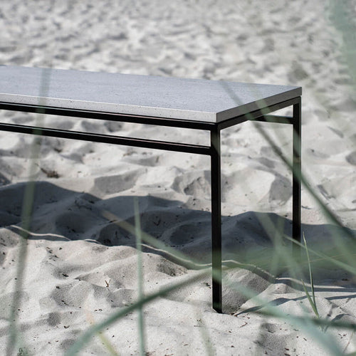 Wilma outdoor bench in black with sleek Keon dekton top, set against sandy background, perfect for gardens.