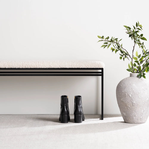 Wilma bench in black with ivory bouclé, stylishly placed beside a vase and black boots, perfect for entryways or bedrooms.