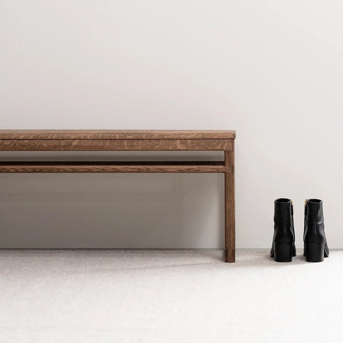 Oak Bench in dark oak frame beside black boots on a neutral background, perfect for hallways or entryways.