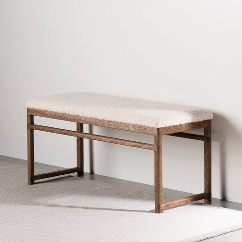 Wilma wood bench in dark oak with ivory bouclé upholstery, ideal for foot of bed or hallway.