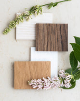Flat lay of oak wood finish samples in whitewashed, natural, and dark stain – paired with soft florals and greenery for by Crea furniture customization.