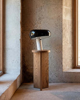 Pedestal Affe - Dark oak with a modern lamp in a stylish indoor setting.