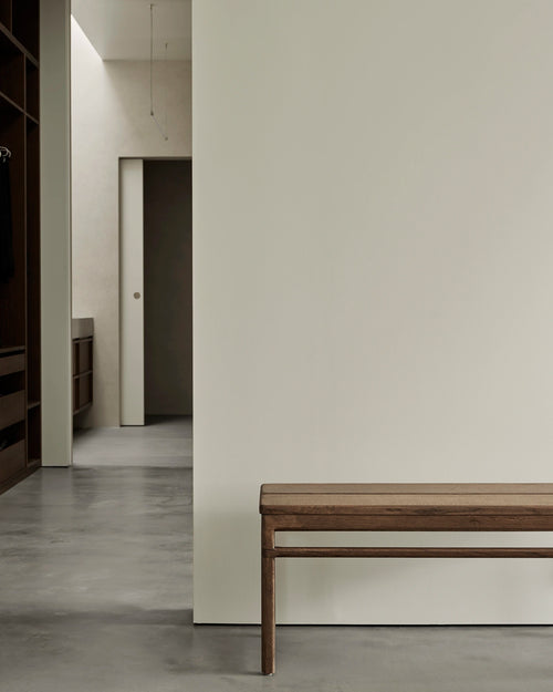 Minimalist dark oak bench in a modern Scandinavian hallway with clean lines and neutral tones.