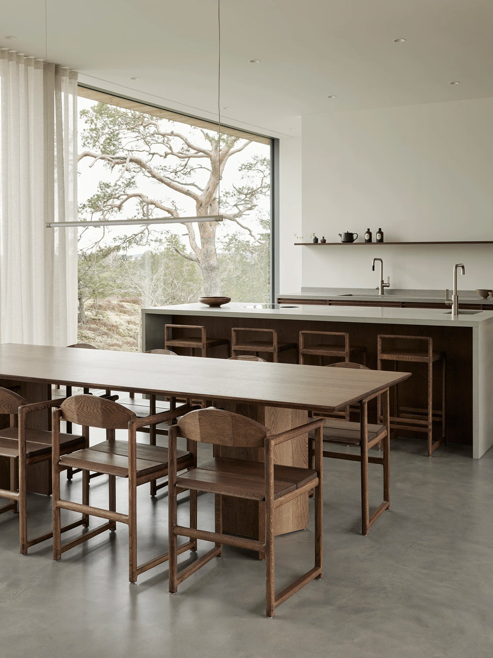 Erik dining chairs and Ebba bar stools in dark oak in a kitchen with panoramic windows at Pine Edge Villa