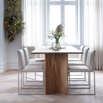 Ann dining table in oak with modern white chairs, showcasing elegance and natural warmth in a stylish dining space.
