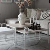 Anton nesting table set with white frame and oak tops, styled in a modern neutral-toned living room.