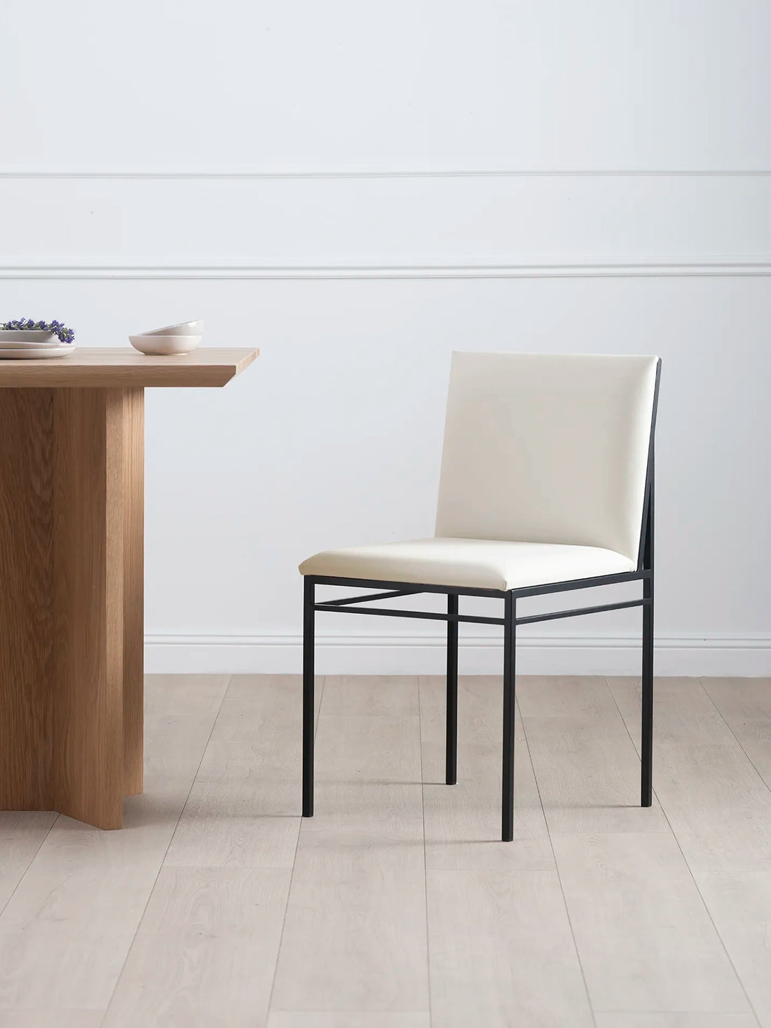 Dining chair Bella features a black frame and ivory leather cushion, perfect for a modern dining space.